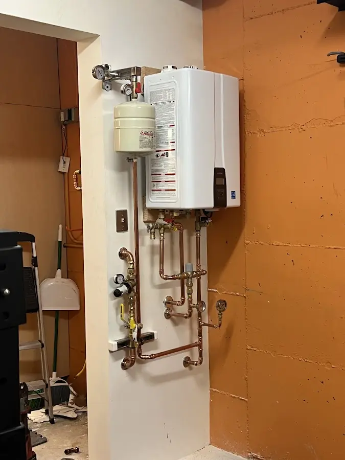 Plumbing technician inspecting water heater connections in Little Silver